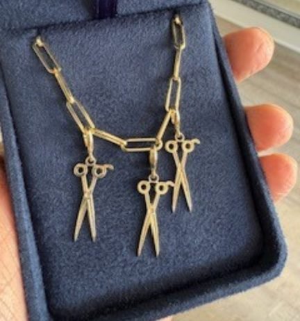 Handcrafted silver necklace featuring three scissor charms, displayed in a blue velvet jewelry box. Ideal for hairstylists or sewing enthusiasts.
