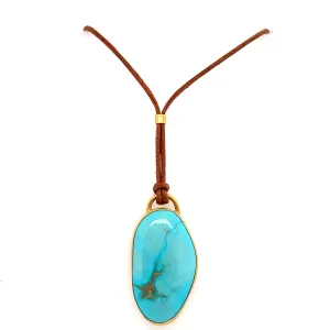 Turquoise pendant necklace featuring a smooth, oval-shaped turquoise stone set in gold trim, suspended from a brown leather cord. Ideal for bohemian or minimalist jewelry styles.