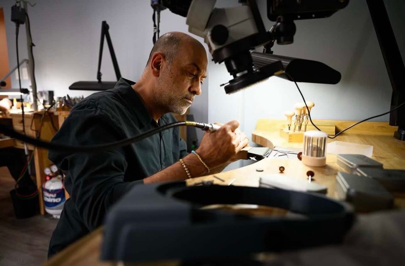 Jeweler focused on intricate craftsmanship, working with tools and materials in a well-lit workshop. The scene showcases a detailed view of the jewelry-making process, highlighting precision and artistry in a professional setting.